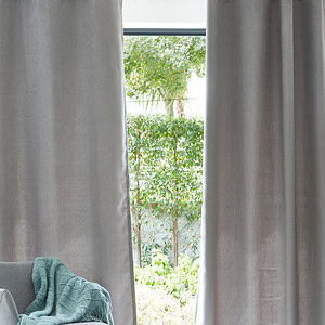 modern wood and white armchair with throw blanket in front of curtains