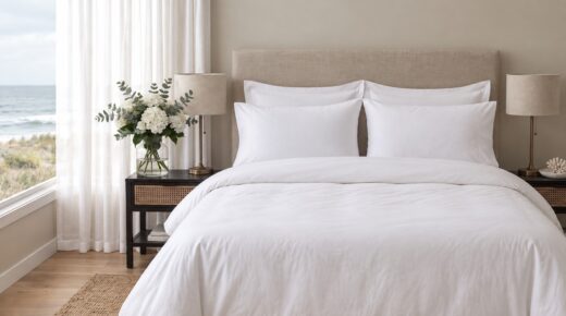 200 Thread Count 100% Cotton Percale Duvet Cover Set - White, Grey & Duck Egg 5 A neatly made bed dressed in crisp white linens, featuring four pillows and a white duvet, set against a beige upholstered headboard in a bright, coastal-style bedroom with dark wood nightstands.